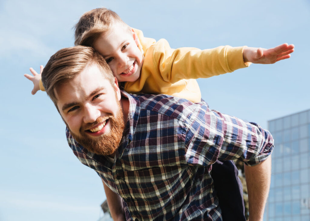 un-padre-sonriente-lleva-a-su-pequeño-hijo-a-cuestas