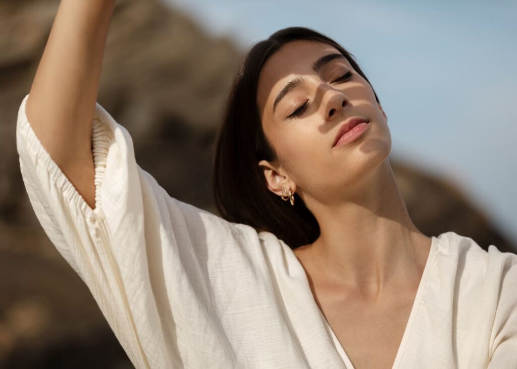 mujer-vestida-de-blanco-con-los-ojos-cerrados-que-se-protege-del-sol-con-la-mano