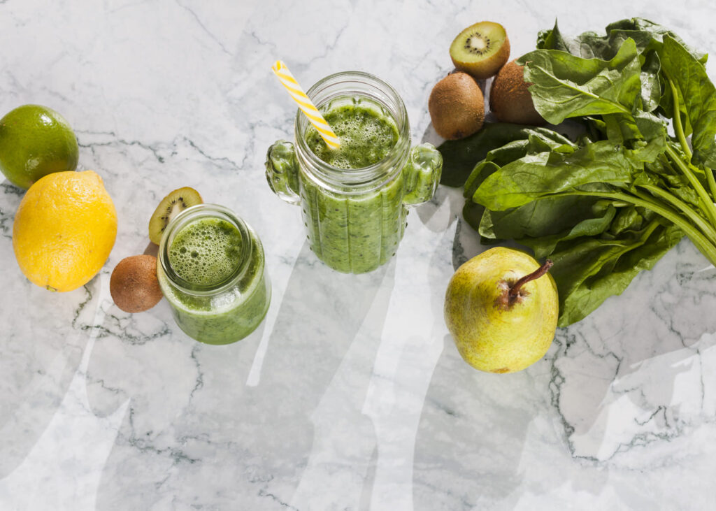 primer-plano-de-un-zumo-detox-y-de-verduras-y-frutas-sobre-una-mesa-con-efecto-marmol