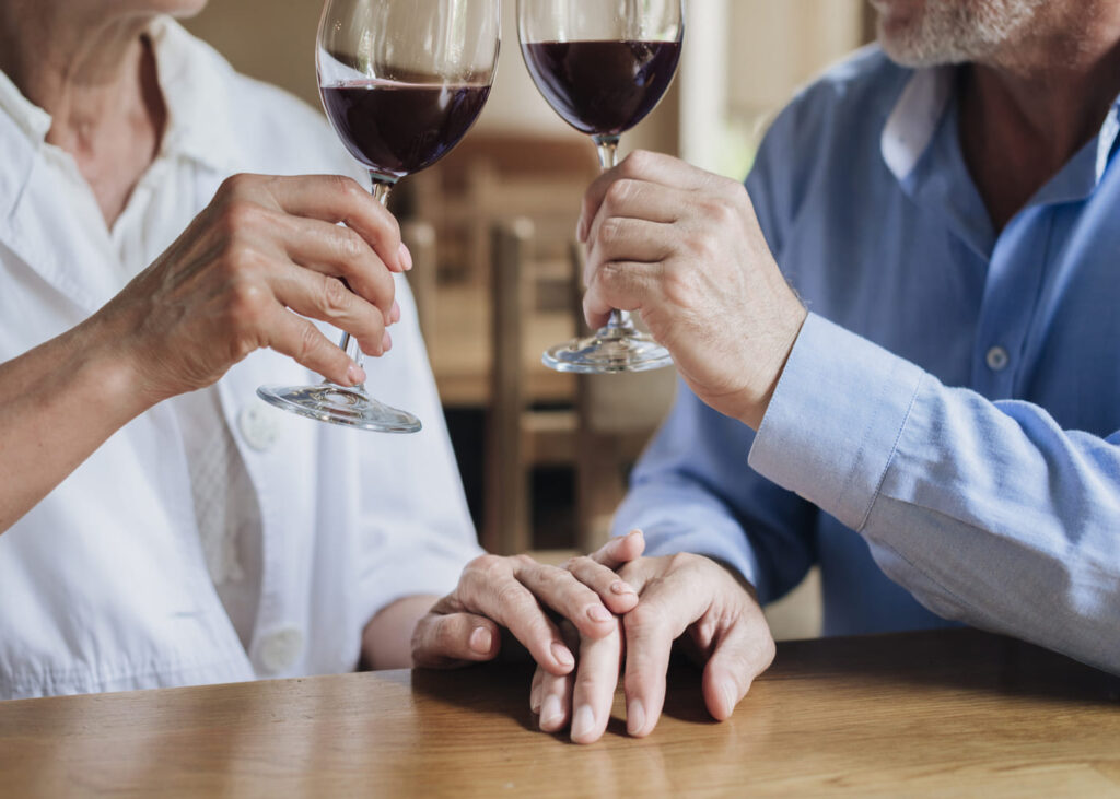 dos-personas-brindando-con-una-copa-de-vino-tinto-en-la-mano