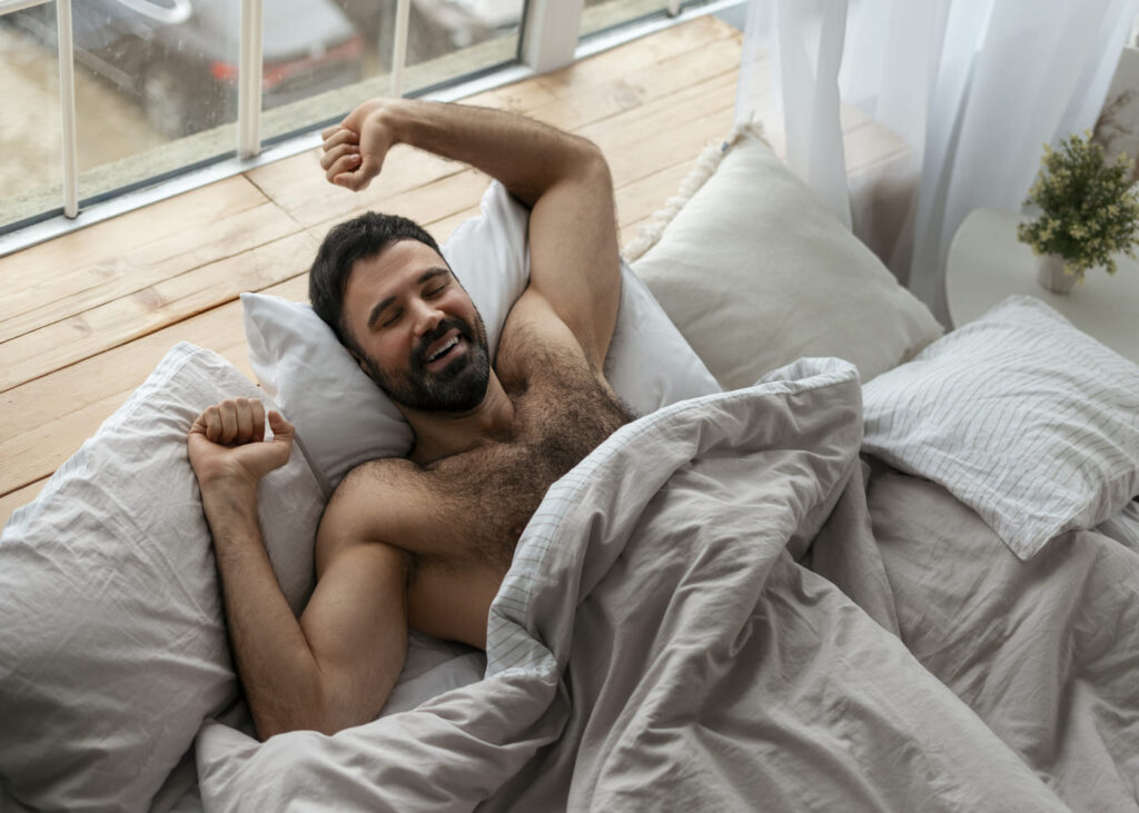 hombre-con-el-torso-desnudo-estirandose-en-su-cama