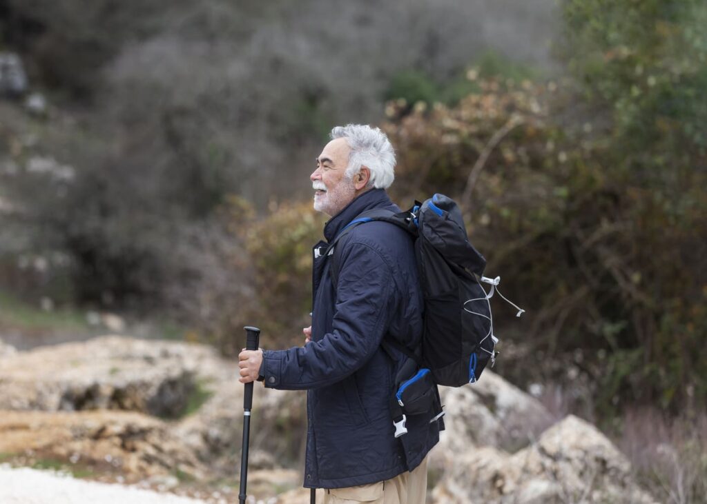 hombre-mayor-haciendo-senderismo-con-bastones-y-mochila