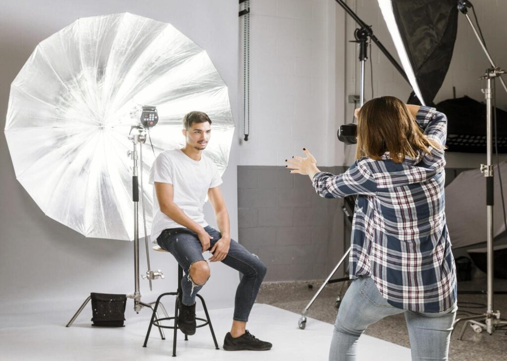 hombre-que-posa-sobre-un-taburete-delante-de-una-fotógrafa-durante-una-sesión-de-fotos