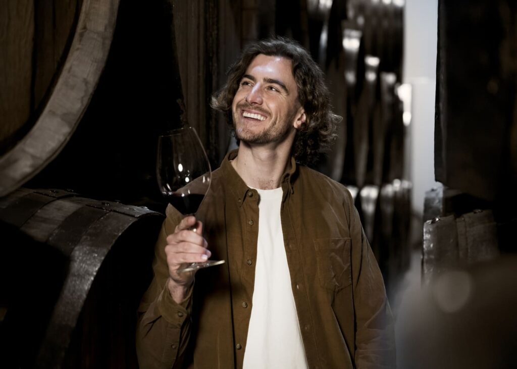 hombre-que-sonríe-en-una-bodega-con-una-copa-en-la-mano