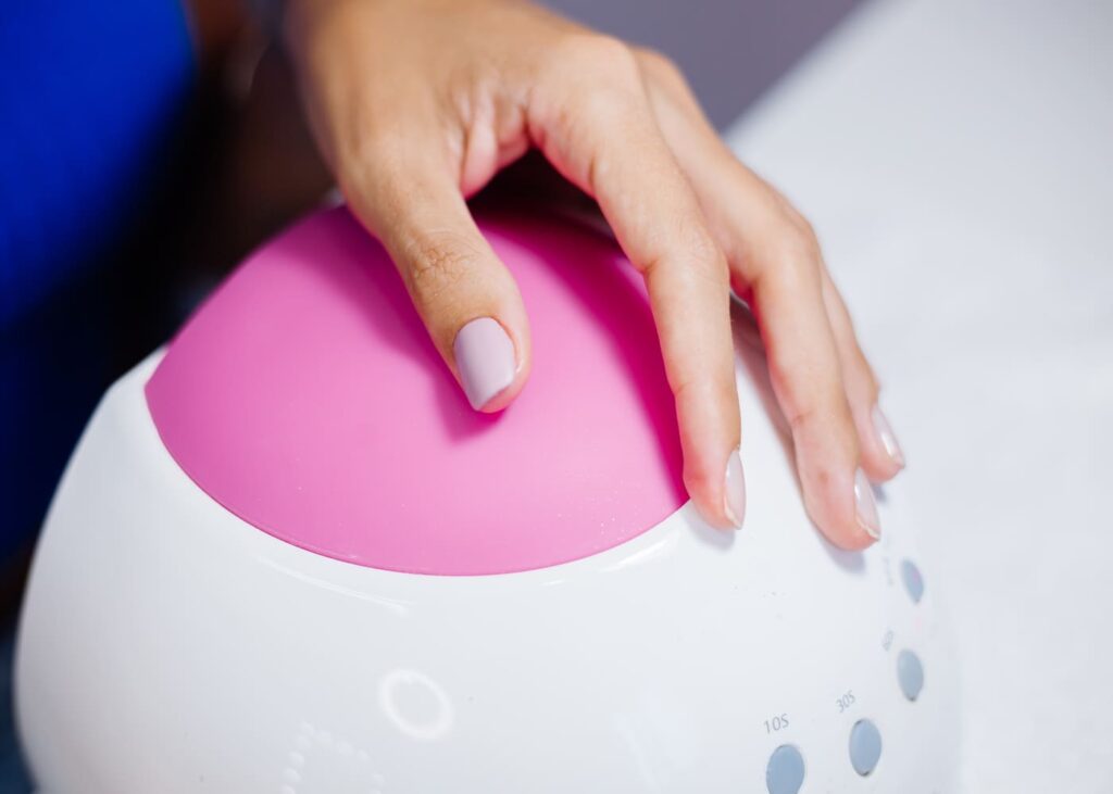 manos-de-mujer-con-esmalte-apoyadas-sobre-una-máquina-para-esmaltado-semipermanente