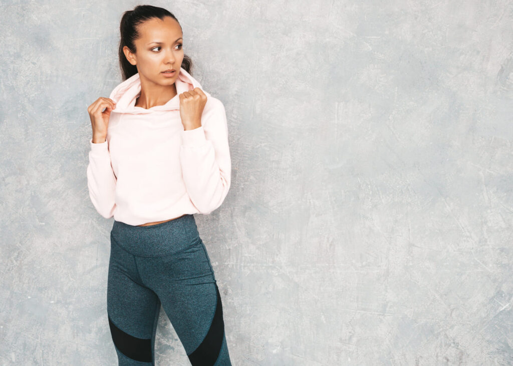 mujer-con-ropa-deportiva-delante-de-una-pared-gris