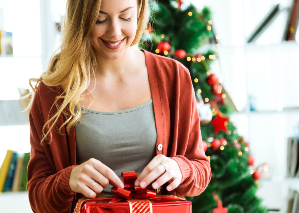 mujer-que-abre-un-regalo-rojo-delante-de-un-arbol-de-navidad