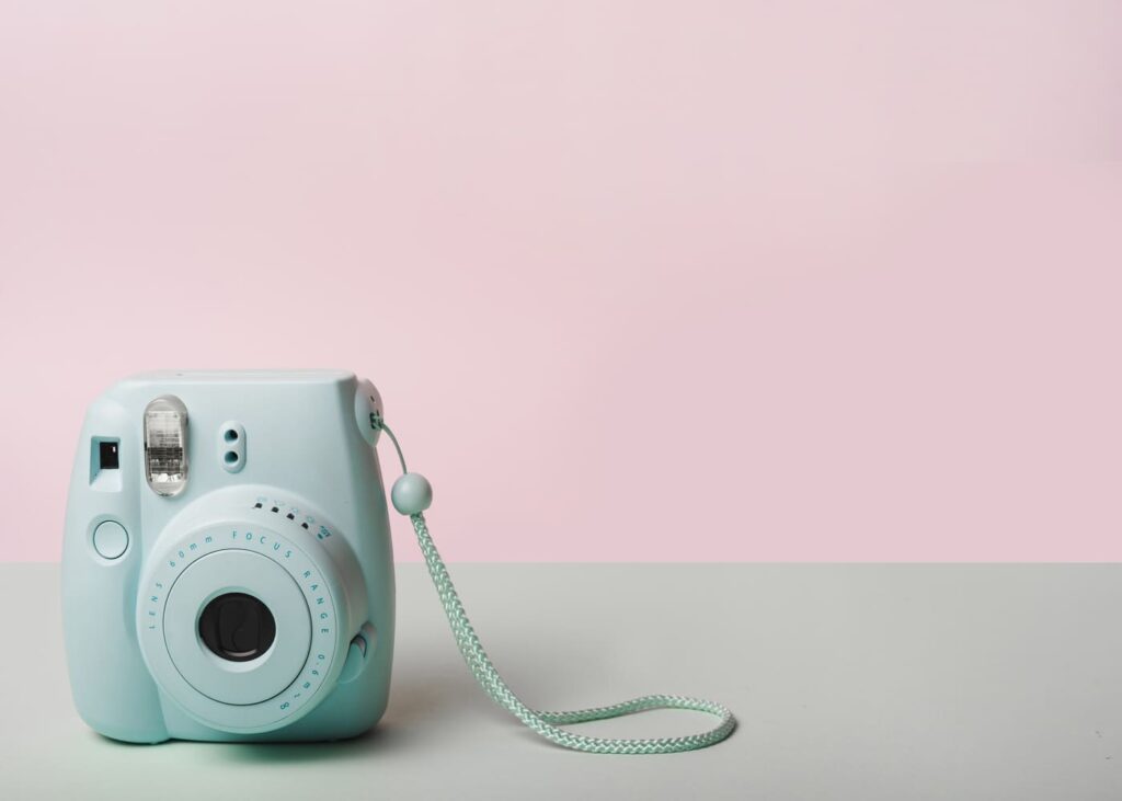 polaroid-verde-colocada-sobre-una-mesa-con-fondo-rosa