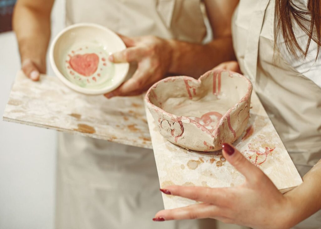 primer-plano-de-manos-de-mujer-sujetando-cada-una-un-bote-de-ceramica-pintado