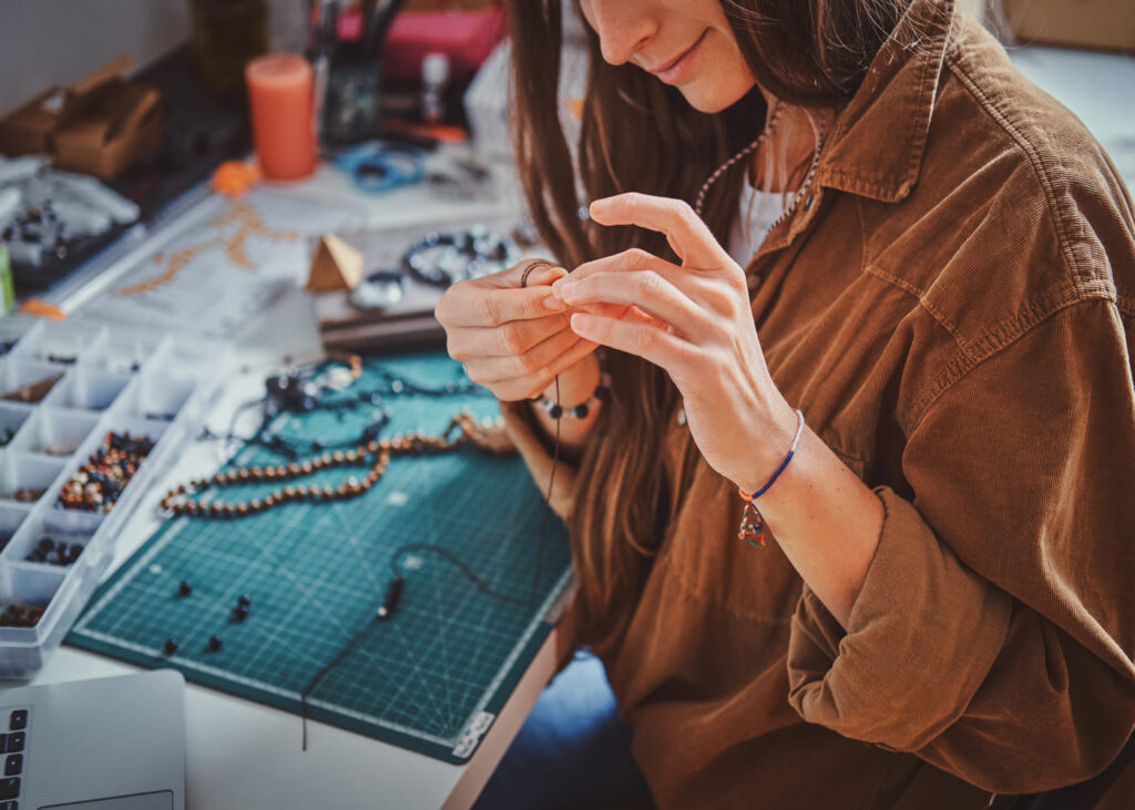 primer-plano-de-una-mujer-sonriente-que-crea-una-joya-con-abalorios