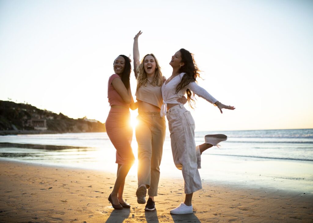 tres-mujeres-que-posan-sonriendo-en-una-playa-frente-al-mar