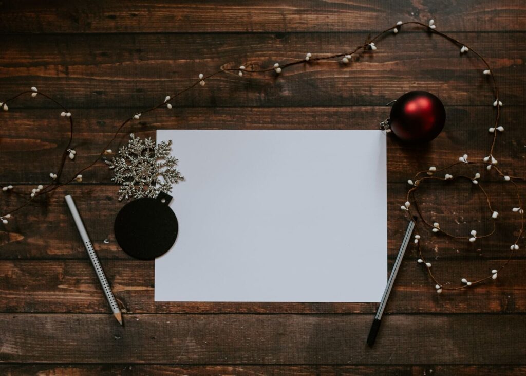 carta-blanca-colocada-sobre-una-mesa-de-madera-con-bolas-de-navidad-alrededor
