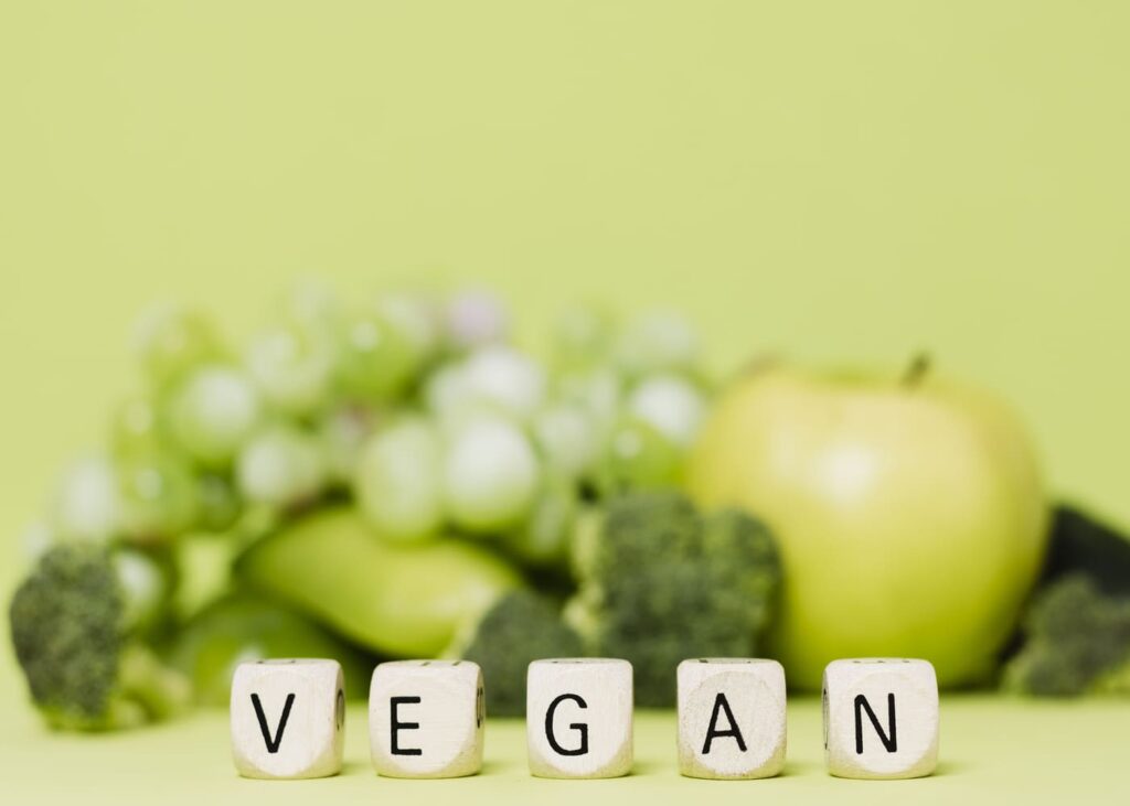 cubos-con-la-palabra-vegan-y-frutas-y-verduras-verdes-de-fondo
