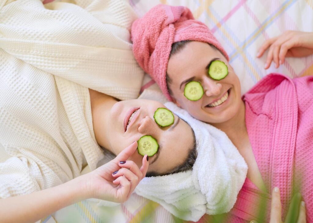 dos-amigas-tumbadas-en-albornoz-con-rodajas-de-pepino-sobre-los-ojos