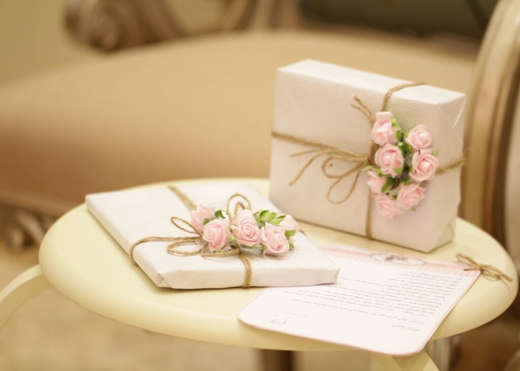 dos-regalos-de-boda-blancos-con-flores-colocados-sobre-una-mesa-blanca