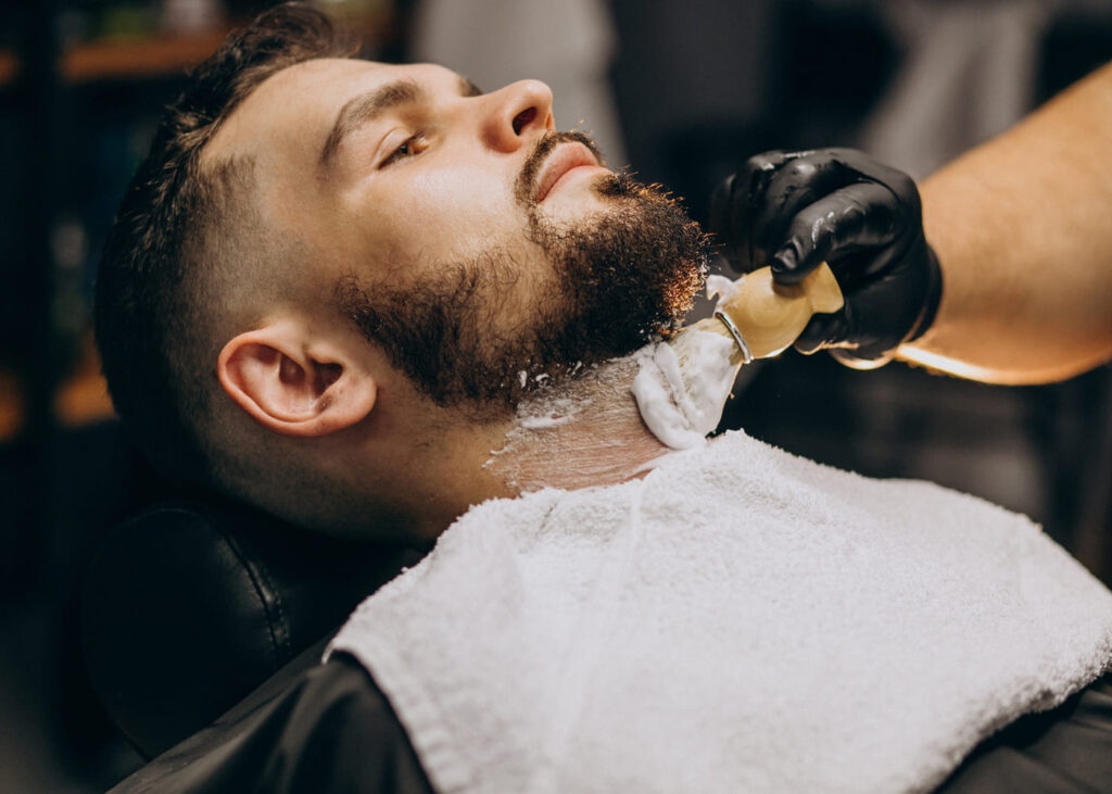 hombre-acostado-que-recibe-un-tratamiento-de-barba-en-una-barbería