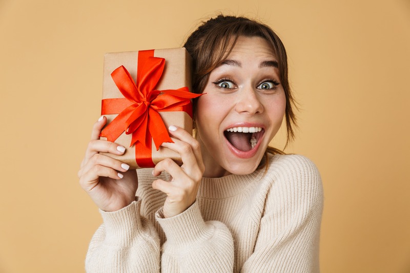 joven-mujer-morena-feliz-que-sostiene-un-regalo-en-sus-manos