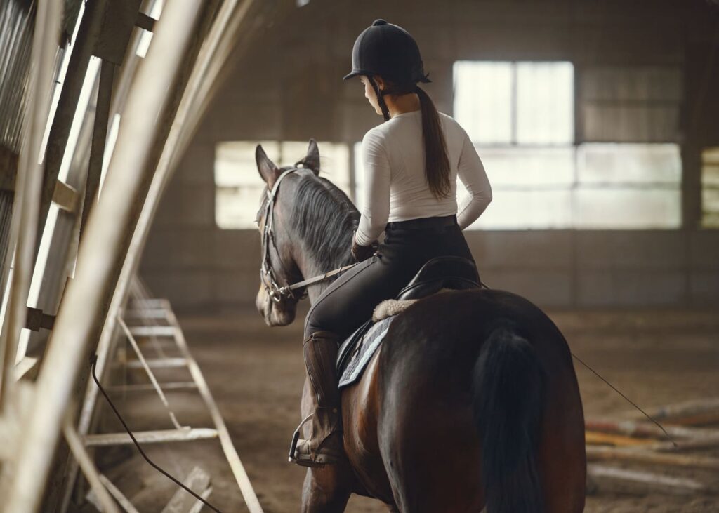 joven-mujer-que-monta-a-caballo-en-un-maneje
