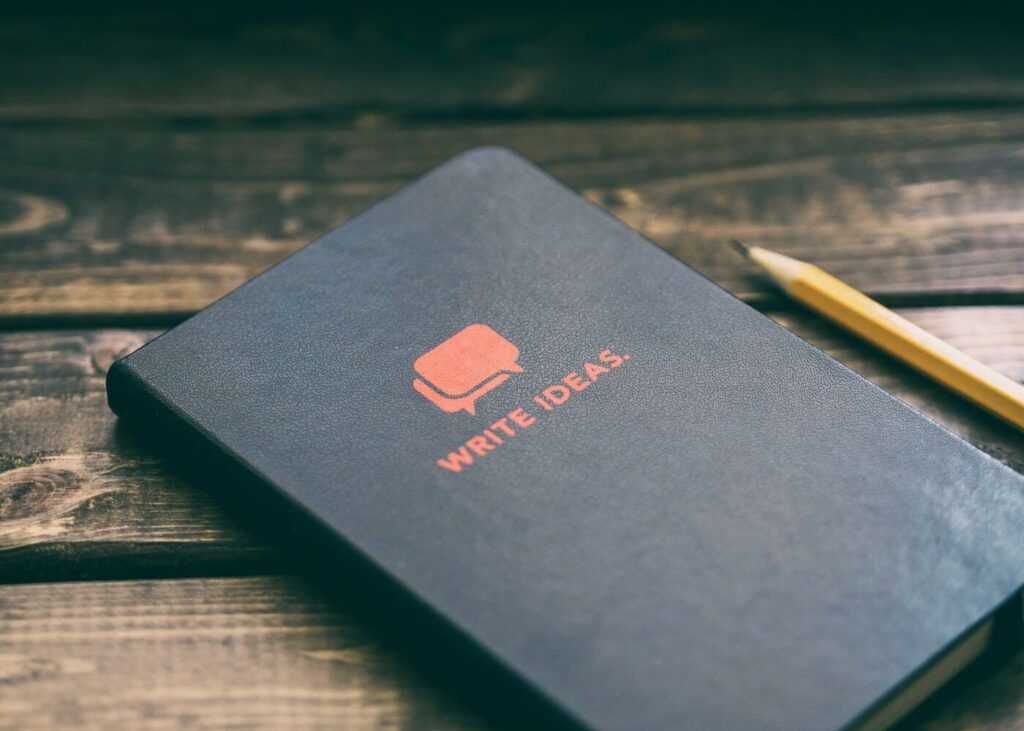 libreta-negra-con-escritura-roja-encima-sobre-una-mesa-de-madera
