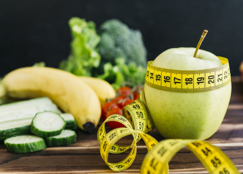 manzana-rodeada-de-un-metro-con-otras-frutas-sobre-una-mesa