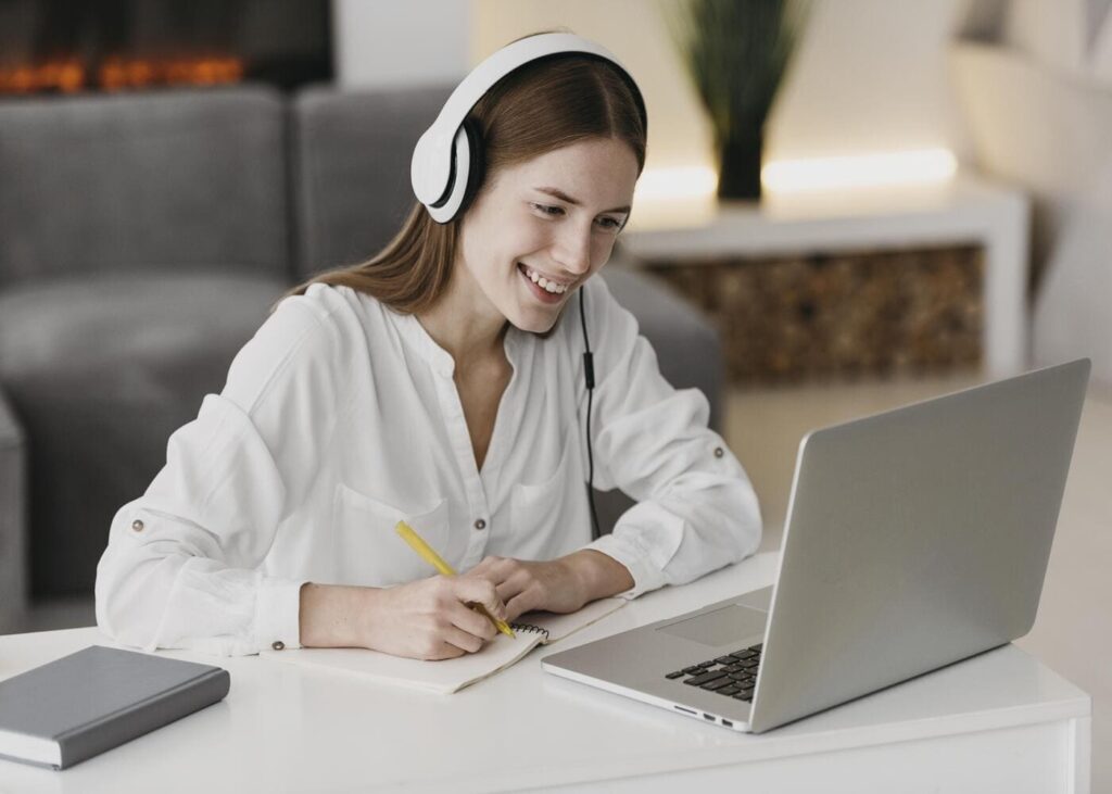 mujer-con-auriculares-sobre-las-orejas-que-sonrie-en-videollamada-en-su-ordenador