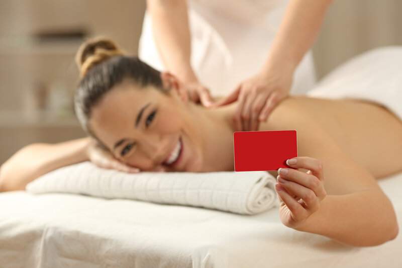 mujer-feliz-que-recibe-un-masaje-sosteniendo-una-tarjeta-roja-en-la-mano