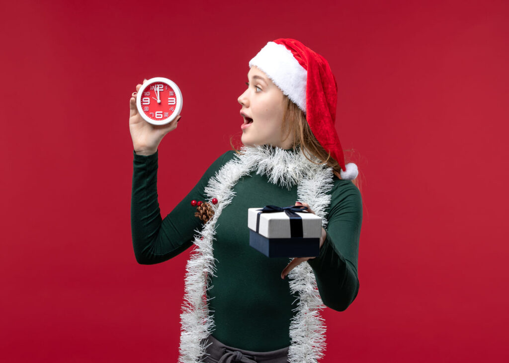 mujer-que-abre-la-boca-y-sostiene-un-reloj-y-un-regalo-en-cada-mano-sobre-fondo-rojo