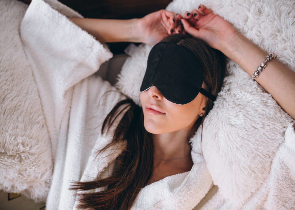 mujer-tumbada-en-una-cama-con-mascarilla-para-dormir