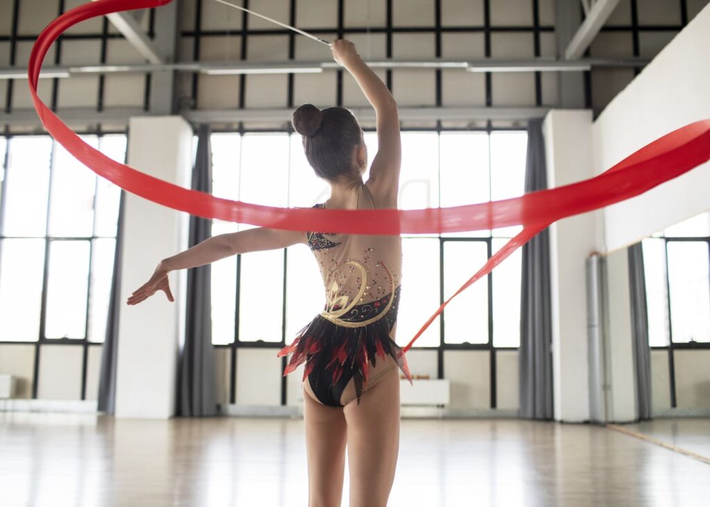 niña-pequeña-con-maillot-de-gimnasia-que-hace-girar-su-cinta