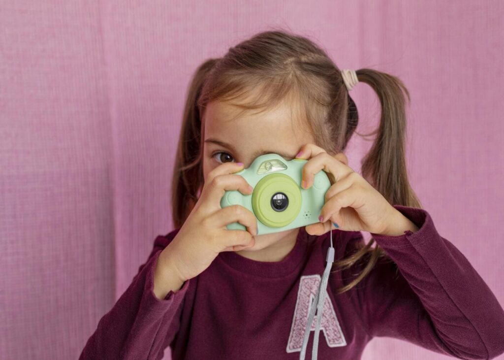 nina-pequena-que-juega-con-una-camara-de-fotos-para-ninos