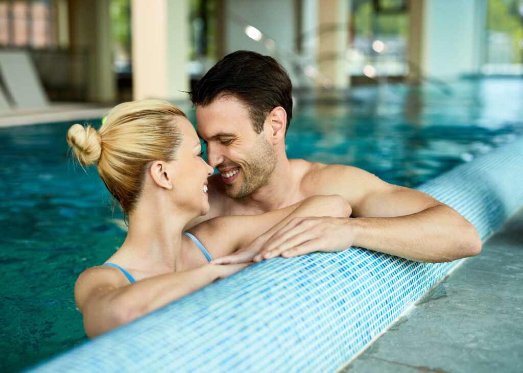 pareja-que-se-mira-sonriendo-en-una-piscina-de-un-spa