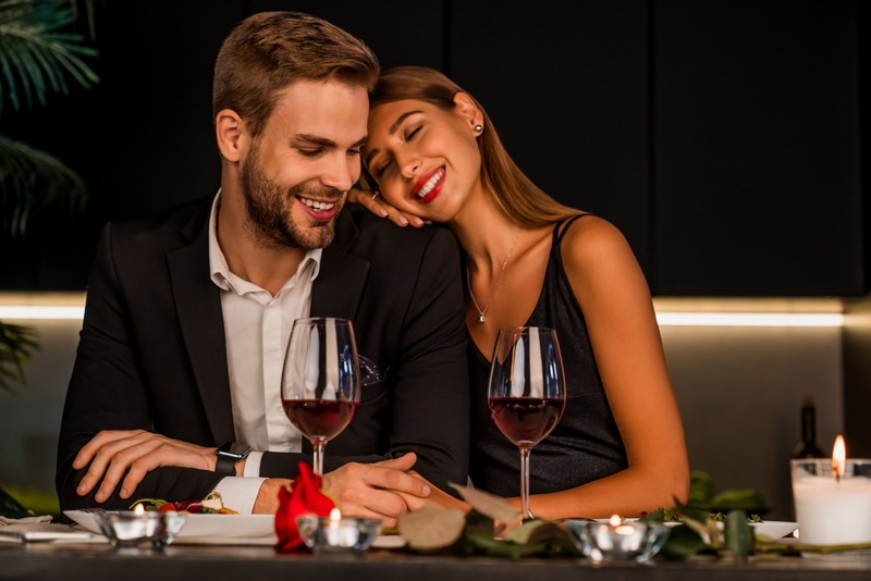pareja-sonriente-que-bebe-una-copa-de-vino-tinto-en-un-restaurante