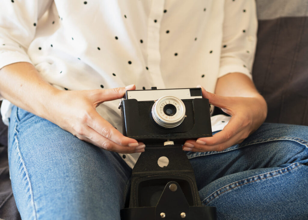 primer-plano-de-la-mano-de-una-mujer-que-sostiene-una-camara-fotografica-vintage