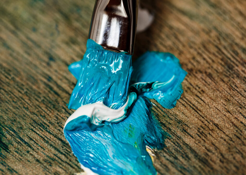 primer-plano-de-un-pincel-con-pintura-azul-sobre-una-mesa-de-madera