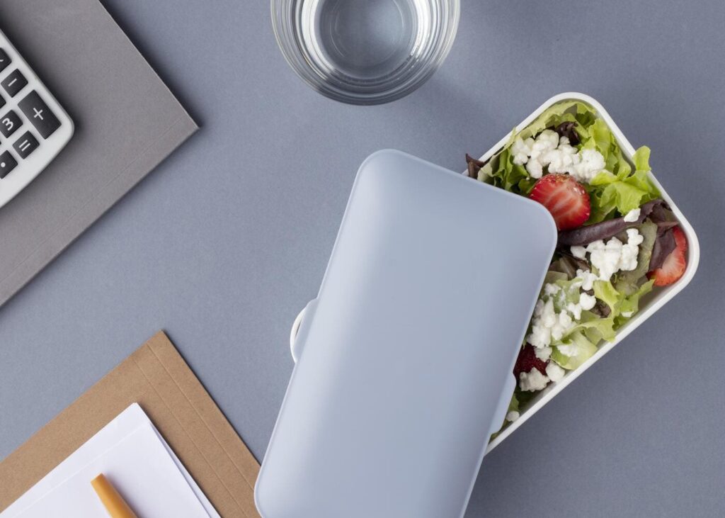 primer-plano-de-un-tupperware-lleno-de-comida-colocado-sobre-un-escritorio-de-trabajo