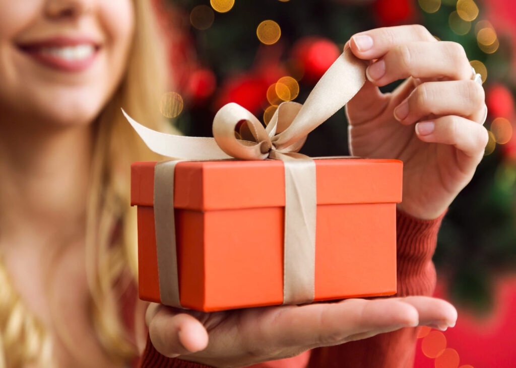 primer-plano-de-una-mujer-rubia-que-abre-un-pequeño-regalo-rojo-en-su-mano