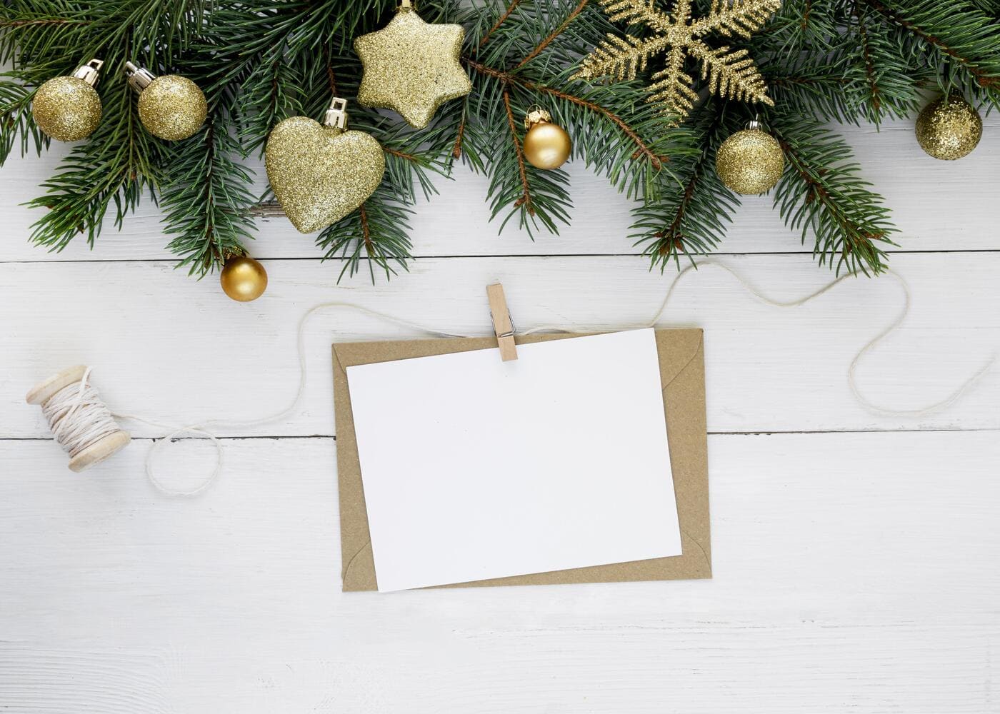 tarjeta-blanca-con-un-sobre-dorado-debajo-de-decoraciones-de-navidad