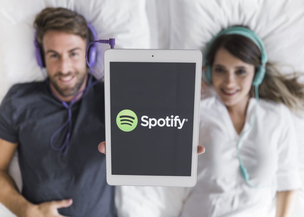 un-hombre-y-una-mujer-acostados-en-su-cama-que-muestran-una-tableta-que-muestra-spotify