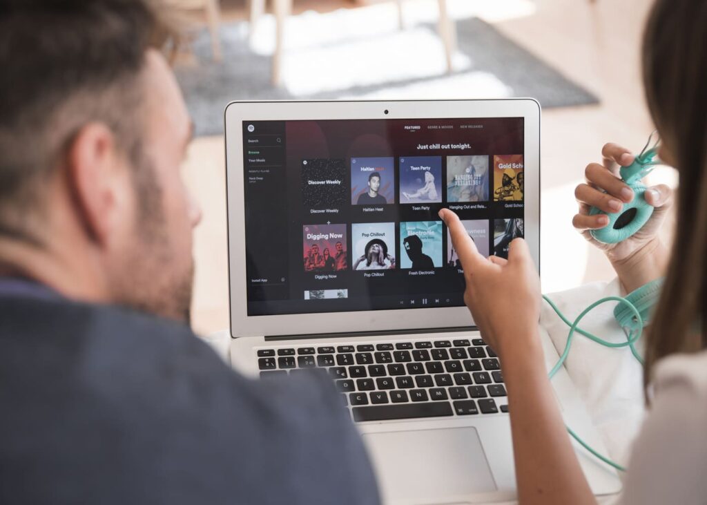 vista-de-espaldas-de-dos-personas-acostadas-en-una-cama-mirando-spotify-en-el-ordenador