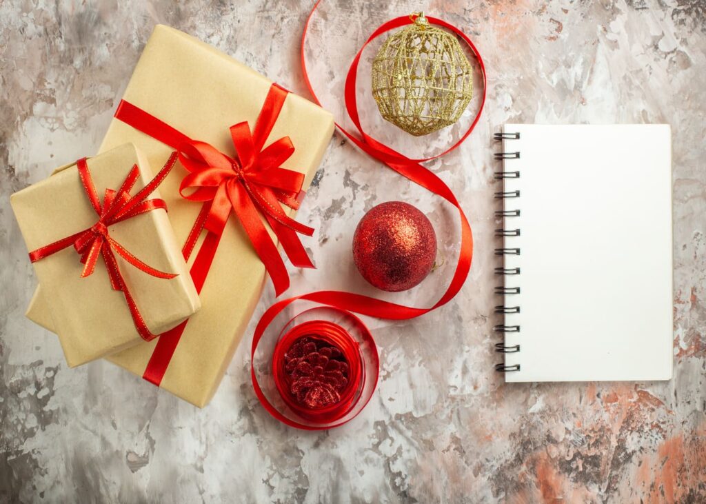 vista-desde-arriba-de-dos-regalos-un-cuaderno-y-decoraciones-de-navidad