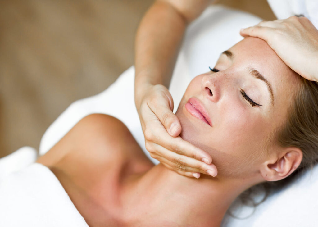 mujer-acostada-con-los-ojos-cerrados-disfrutando-de-un-masaje-facial-en-un-centro-de-estetica