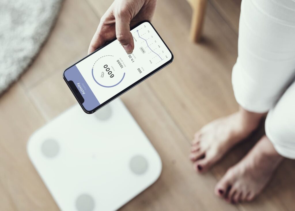 primer-plano-de-una-persona-usando-una-bascula-inteligente-con-su-telefono